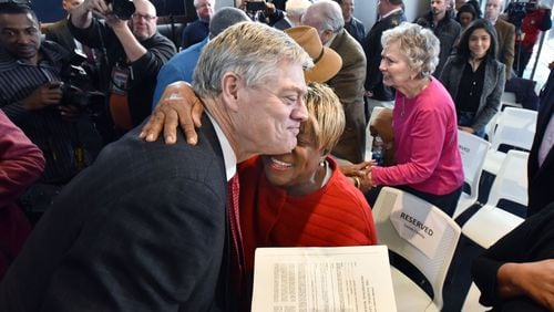 Rubye Lucas, wife of the late Bill Lucas, hugs former Braves star Dale Murphy on Thursday as he holds a copy of his 1978 contract, signed by Lucas. HYOSUB SHIN / HSHIN@AJC.COM