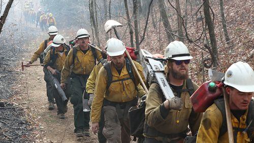 An incoming California fire crew (right) walks in after working over night on the northern head of the Rock Mountain Fire along the Appalachian Trail at Deep Gap while a outgoing Oregon fire crew (far left) bumps them heading out for their long shift on Tuesday, Nov. 22, 2016, north of Tate City and the North Carolina border. The area is deep in the Natahala National Forest. Curtis Compton/ccompton@ajc.com