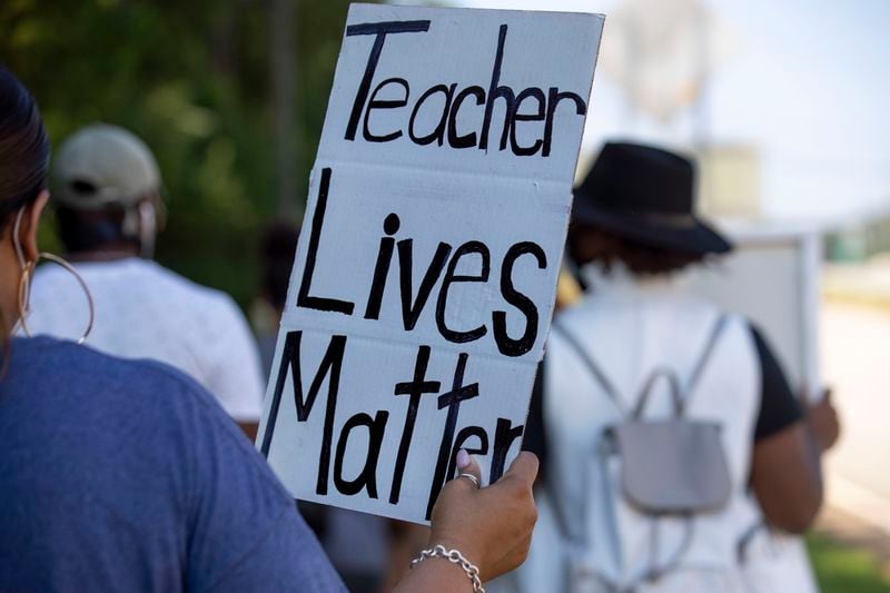 Members of the Gwinnett Educators for Equity and Justice group and their supporters carry signs as they march down Old Peachtree Road NW, in Suwanee, on July 20.  (ALYSSA POINTER / ALYSSA.POINTER@AJC.COM)