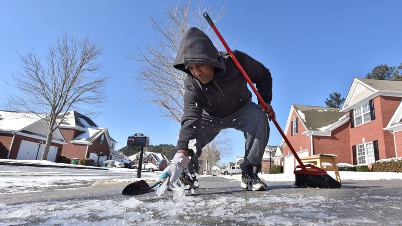  Israel Hora tries to clear her driveway of ice with a garden trowel in Snellville on Wednesday, January 17, 2018. HYOSUB SHIN / HSHIN@AJC.COM