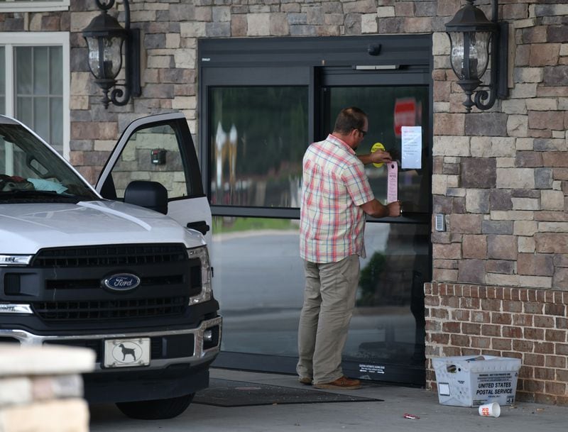A crew from Cherokee County Water and Sewerage Authority posts a "Water Disconnected" notice on the front door of Tranquil Gardens Assisted Living & Memory Care in Acworth on Wednesday.(Hyosub Shin / Hyosub.Shin@ajc.com)