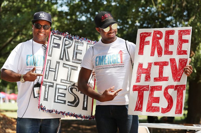 Reggie McKenzie (left) and Jamie Allen encourage attendees to get a free AIDS test as part of Black Gay Pride weekend in 2016. Curtis Compton /ccompton@ajc.com AJC File Photo