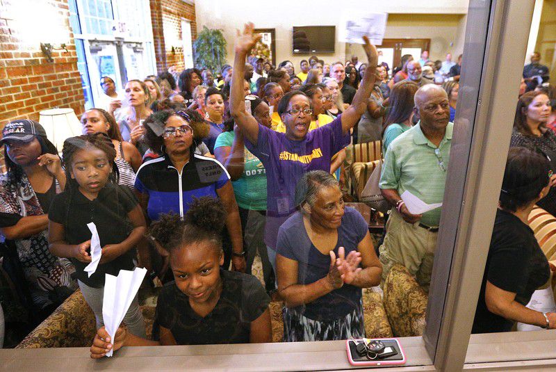 An overflow crowd reacts from the lobby during the Buford Board of Education meeting at the Central Office board room on Aug. 27. It was the first meeting since Superintendent Geye Hamby resigned amid allegations he used racial slurs to refer to black temporary construction workers and threatened violence against them. (Curtis Compton / ccompton@ajc.com)