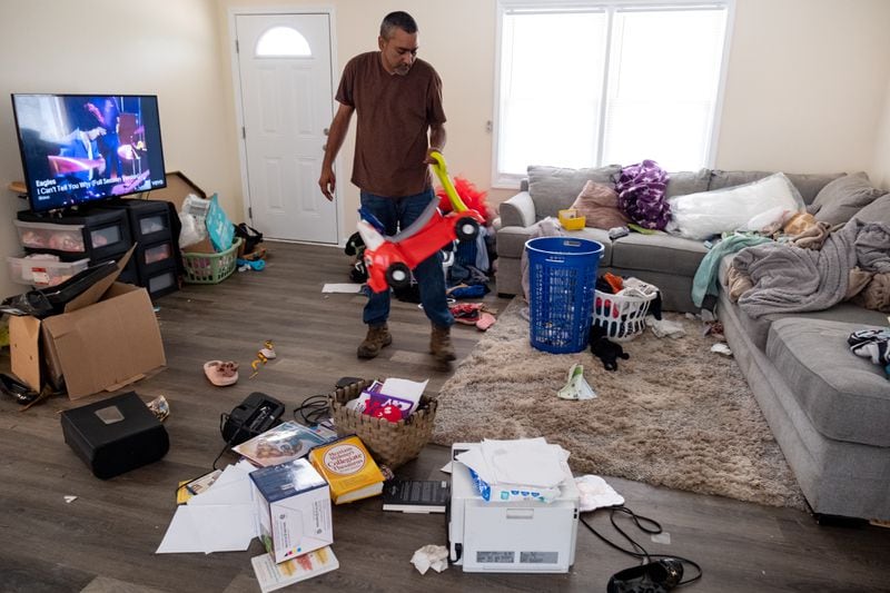 Rajesh Desor tries to organize belongings after a sewage backup forced his family from their Stone Mountain rental home just weeks after moving in. Three weeks after the backup, the rental company still hadn't cleaned or repaired the house to a condition they’re comfortable living in. (Ben Gray / Ben@BenGray.com)