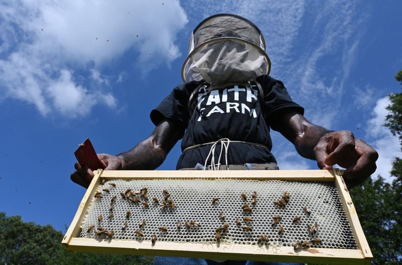William Crumpler II, known as “Bill the Bee Man”, holds a section of a bee hive during an educational event to learn harvesting honey and beekeeping at Metro Atlanta Urban Farm, Thursday, July 6, 2023, in College Park. (Hyosub Shin / Hyosub.Shin@ajc.com)
