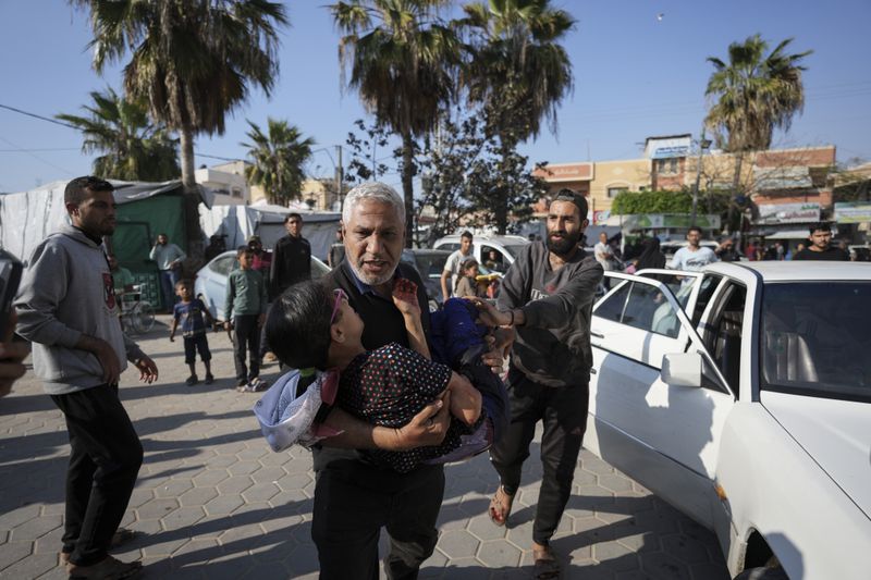 A Palestinian man carries a wounded boy following an Israeli bombardment in the Maghazi refugee camp, central Gaza Strip, Tuesday, April 16, 2024. Several killed in a strike in Maghazi camp in Central Gaza on Tuesday. (AP Photo/Abdel Kareem Hana)