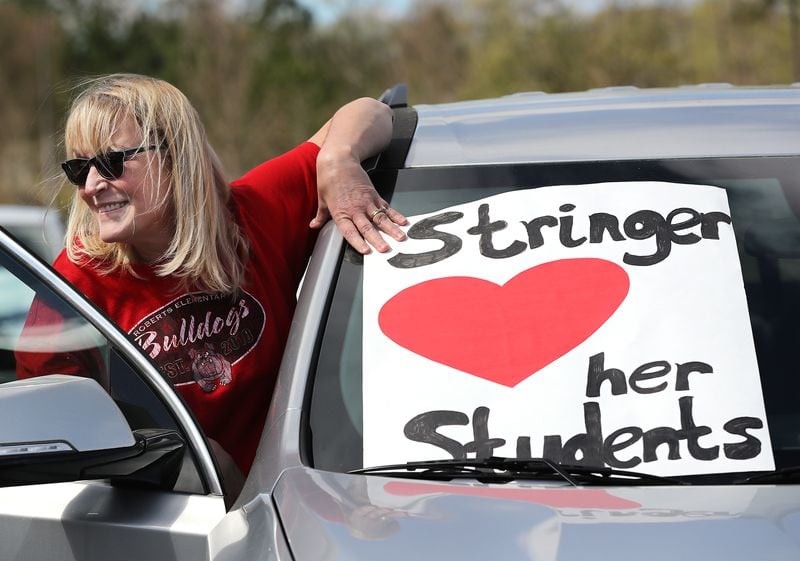 Second through fifth grade teacher Angie Stringer lets her students know she loves them while teachers from Roberts Elementary hold an inspirational school parade driving through nearly two dozen area neighborhoods for some face-to-face contact while still maintaining social distance to ease the separation anxiety of their students during the coronavirus on Wednesday, March 25, 2020, in Suwanee. Although distance learning is allowing kids to connect with teachers and get lessons done, the personal touch is missing.       