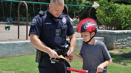 Gage McPherson, 10,  was “Caught by a Cop” in Etowah River Park on Thursday, July 20, 2017, for wearing a bicycle helmet. Officer Adam Yurkousky issued him a ticket and he was given a coupon for a Chick-fil-A sandwich after he signed the citation and agreed to continue to wear his helmet.