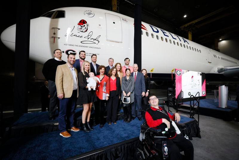 Family members, including Barbara Dooley, pose in front of the aircraft moments after delta Airlines honored Hall of Fame University of Georgia coach Vince Dooley with a plane dedication on Tuesday, January 3, 2022, at Hartsfield-Jackson International Airport. (Miguel Martinez/The Atlanta Journal-Constitution)