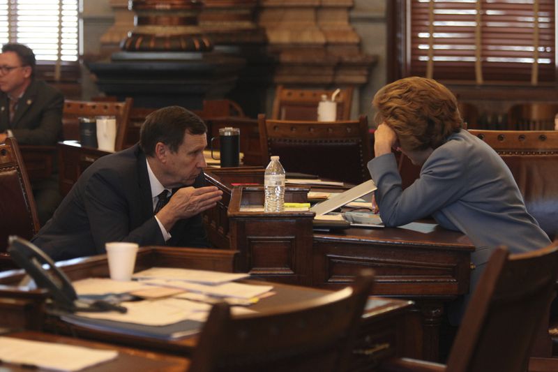 Kansas state Sen. Dennis Pyle, left, R-Hiawatha, confers with Sen. Brenda Dietrich, R-Topeka, during the Senate session, Friday, April 5, 2024, at the Statehouse in Topeka, Kan. Pyle supports a bill to make it a crime to coerce someone into having an abortion, while Dietrich passed the last time senators considered it. (AP Photo/John Hanna)