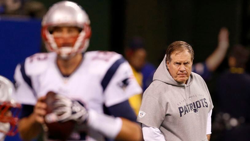 New England Patriots head coach Bill Belichick watches as quarterback Tom Brady (12) warm up.