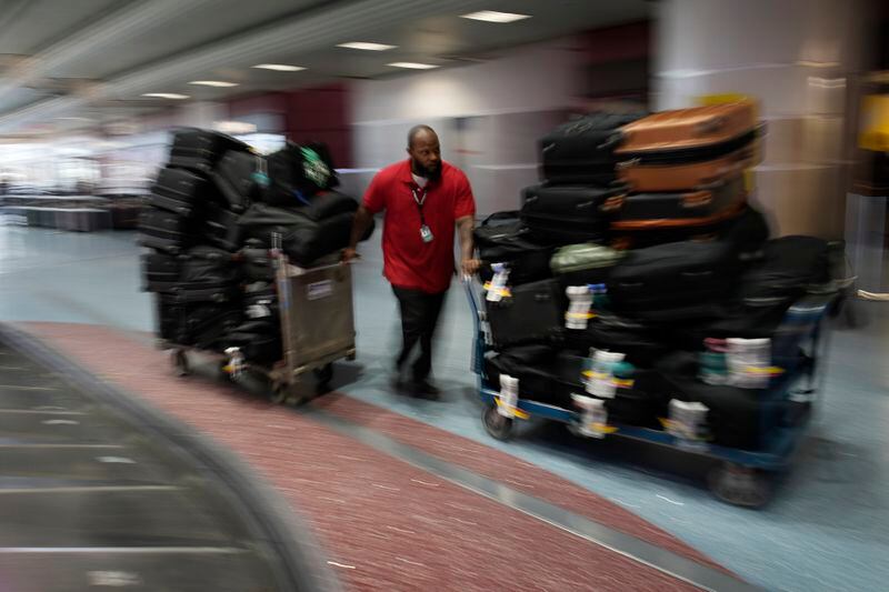 FILE -Leo Stevens, a baggage handler at Harry Reid International Airport, helps move bags belonging to the New York Liberty WNBA basketball team, Wednesday, June 28, 2023, in Las Vegas. The wait for full-time charter flights for WNBA teams finally is over with commissioner Cathy Engelbert announcing the league’s plans to start the program this season, Tuesday, May 7, 2024. (AP Photo/John Locher, File)