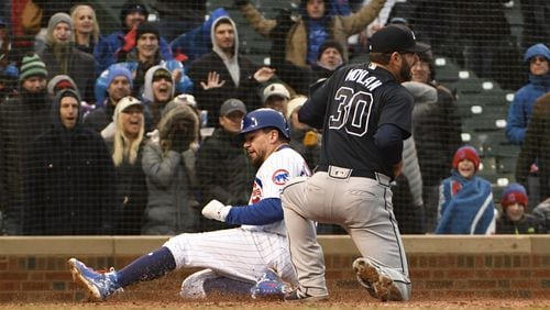Kyle Schwarber #12 of the Chicago Cubs  scores on a wild pitch as Peter Moylan #30 of the Atlanta Braves covers home plate during the eighth inning on April 14, 2018 at Wrigley Field  in Chicago, Illinois. The Cubs won 14-10. (Photo by David Banks/Getty Images)