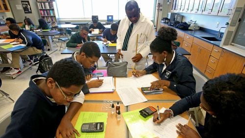 Chemistry teacher Fred Okoh, top center, looks over the work of sophomore students in his classroom at Arabia Mountain High School in this AJC file photo. Once again, Arabia Mountain High has one of the highest four-year graduation rates in DeKalb County.