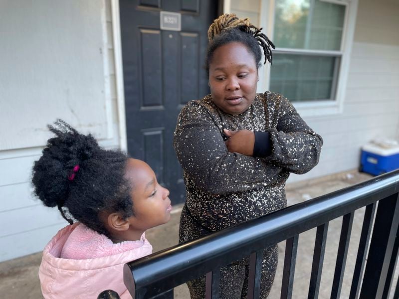 FILE - Tameka and her 8-year-old daughter talk on their porch in Atlanta on Dec. 5, 2023, about when she might start school. Four months after The Associated Press wrote about this Atlanta family struggling to enroll in school, all of the children — in a complete turnaround — returned to class last month.. (AP Photo/Bianca Vázquez Toness, File)