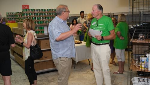 Ronald Robbins (right) chats with volunteer Jack Linder at the recent ribbon cutting of Backpack Buddies’ new Dunwoody food bank.