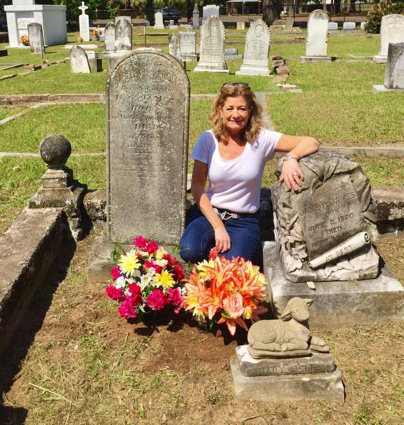 Author Kim Carter poses by the headstone of "Baby Belle" who inspired a plot twist in one of her mystery novels.