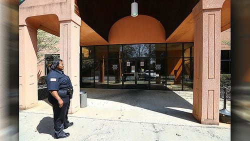 A lone security guard stood watch outside the closed Georgia Department of Labor on Thursday, March 26, 2020, in Marietta. A notice posted in the window advised GDOL was temporarily closing its career centers to the public. Please visit www.gdol.ga.gov for access to online resources.