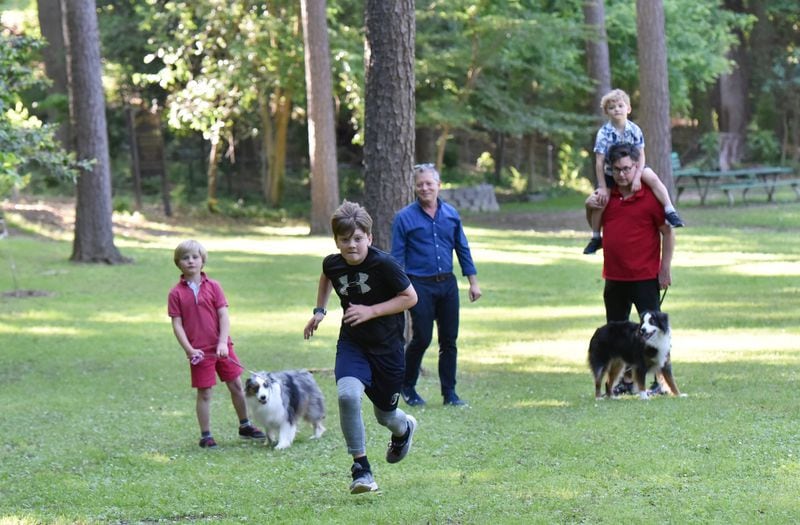 Jackson, 10, shows off his running skill as Hunter, 6, with dog Sophie, parents Matthew Simon and Keith Schumann, Owen, 4, and dog Oliver enjoy the park. HYOSUB SHIN / HSHIN@AJC.COM