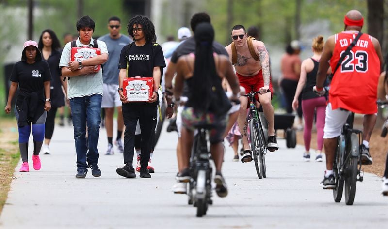 March 29, 2020 Atlanta: Alex Guiterrez (left) and Gavin Studdard make their way home through the crowd on the Atlanta BeltLine trail while making a beer run on Sunday, March 29, 2020, in Atlanta.   Curtis Compton ccompton@ajc.com