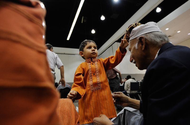 Seventeen months -old Pakistani Muslim Ali Khaja gives his hat to his grandfather Ahsan Khaja before for the special 2011 Eid ul-Fitr morning prayer in Los Angeles, California.