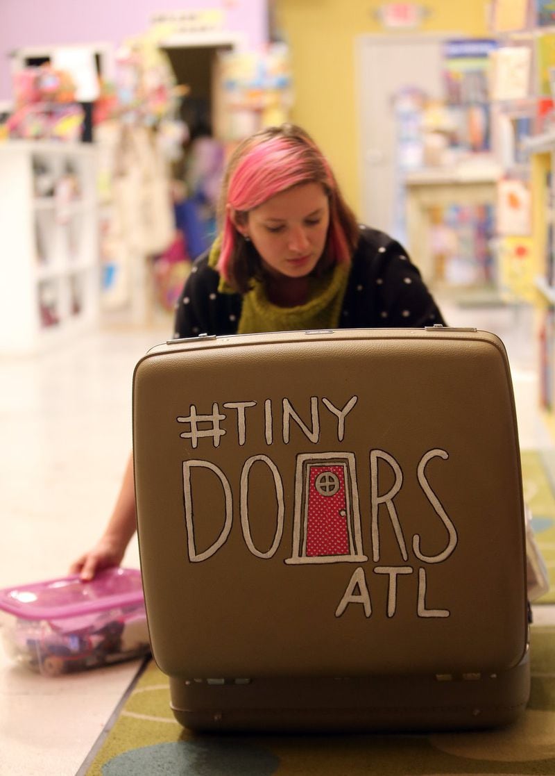 Karen Anderson of Tiny Doors ATL packs up her tools after installing a tiny door and bookcase at Little Shop of Stories in downtown Decatur in January 2015. She’s back at it, creating an entire tiny library that will be in a window of the bookstore. AJC FILE PHOTO