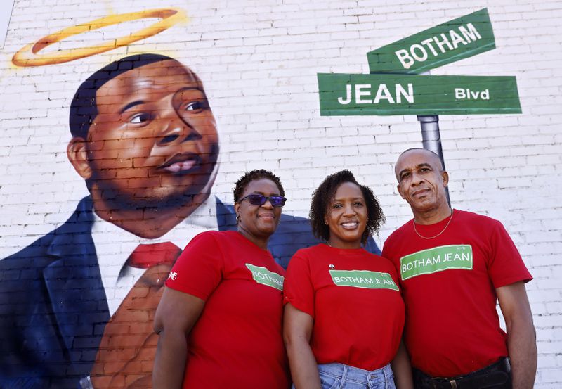 Allison Jean, her daughter Alissa Charles-Findley and husband Bertram Jean pose for a photo before a painted portrait of their slain son and brother, Botham Jean, near downtown Dallas. (Tom Fox/The Dallas Morning News/TNS)