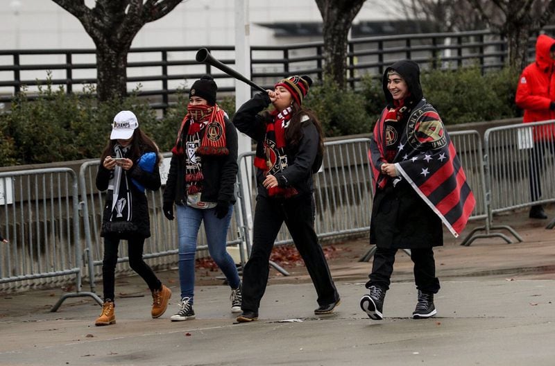 Wearing the team colors, Atlanta United fans begin to arrive 9 a.m. Monday at the Home Depot Backyard for a pep rally and celebration of the MLS Championship win. (Alyssa Pointer/AJC)