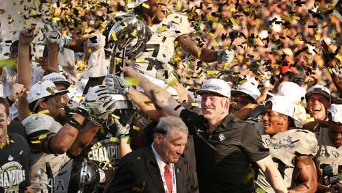 UCF head coach Scott Frost and players celebrate amid falling confetti with the championship trophy after winning the American Athletic Conference Championship Game at Spectrum Stadium Saturday, Dec. 2, 2017 in Orlando. UCF won the game and the AAC title 62-55 in double overtime. (Stephen M. Dowell/Orlando Sentinel)
