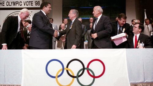 Mayor Maynard Jackson shakes the hand of IOC President Juan Antonio Samaranch after winning the Olympic bid, on Sept. 18, 1990. Seated at right is Atlanta Organizing Committee President Billy Payne. AJC File / W.A. Bridges Jr.