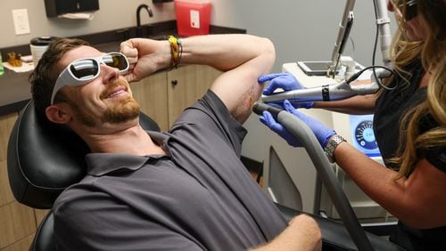 Rob Eskew gets a tattoo removed at Removery Studio in Sandy Springs. The process typically takes several appointments. (Arvin Temkar / arvin.temkar@ajc.com)