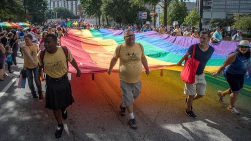 Marchers carry a large rainbow flag up Peachthree Street during Sunday’s Atlanta Pride Parade. STEVE SCHAEFER / SPECIAL TO THE AJC