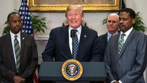 President Donald J. Trump (C), alongside president for the Martin Luther King, Jr. Center Isaac Newton Farris, Jr.(R) and Secretary of Housing and Urban Development Ben Carson (L), speaks before signing a proclamation to honor Dr. Martin Luther King, Jr. Day in the Roosevelt Room of the White House. The President did not respond to shouted questions about whether he is a racist, in response to his referring to Haiti and African nations as "shithole countries."