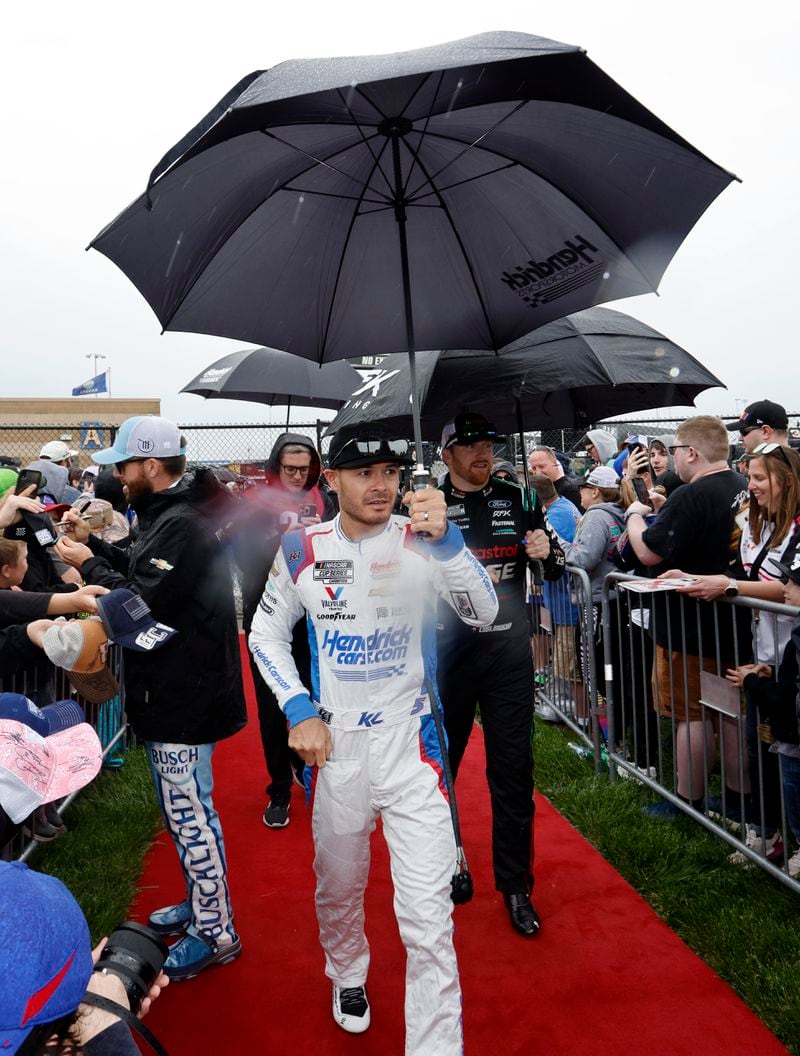 NASCAR Cup Series points leader Kyle Larson, center, walks to a track meeting as rain falls before a NASCAR Cup Series auto race at Kansas Speedway in Kansas City, Kan., Sunday, May 5, 2024. (AP Photo/Colin E. Braley)