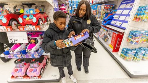 Sergeant Dreyer helps Kaleb Whidby, 9, make a decision about one of his purchases during the Shop With The Sheriff event at the Target at Atlantic Station Saturday, Dec. 9, 2023.  (Steve Schaefer/steve.schaefer@ajc.com)