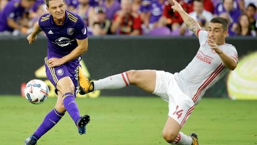 Orlando City's Will Johnson, left, takes a shot on goal as Atlanta United's Carlos Carmona (14) comes in to defend during the first half of an MLS soccer match, Friday, July 21, 2017, in Orlando, Fla. (AP Photo/John Raoux)
