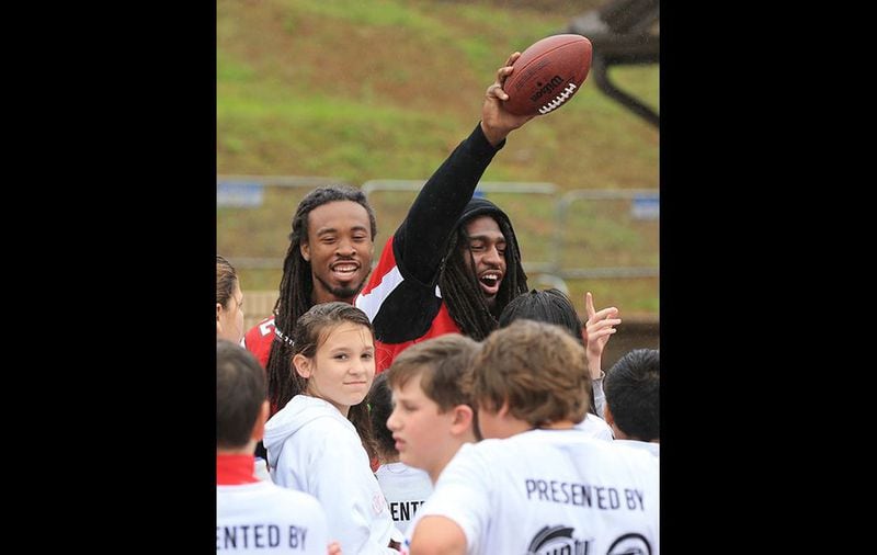 Falcons cornerback Dezmen Southward (left) and safety Kemal Ishmael gather their squad for drills during the NFL PLAY 60 Character Camp Tuesday, Nov. 3, 2015, at Gainesville High School. (Curtis Compton/www.ajc.com)