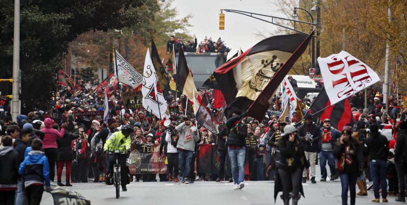 12/10/18 - Atlanta - A double decker bus carrying the team follows cheering fans down Baker Street.  Atlanta United fans  crowded  downtown Atlanta streets to cheer the Atlanta United soccer team and fans in a parade to celebrate winning the MLS Cup, Monday, Dec. 10, 2018.  Bob Andres / bandres@ajc.com