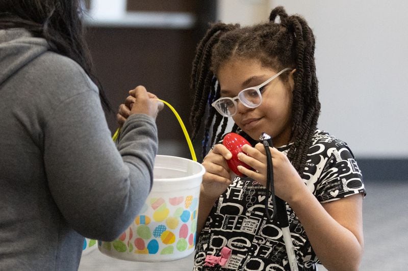 Bri'ehl Rollison, 11, puts a beeping modified Easter egg that she found in her basket during the Beeping Easter Egg Hunt at Acworth Community Center on Saturday, March 23, 2024. The Cobb County Police Department bomb team puts together the special beeping eggs so visually impaired children can find them. (Steve Schaefer/steve.schaefer@ajc.com)