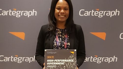 Nadine Bennett-Darby, CCDOT geographic information system (GIS) solutions analyst, shows the award she accepted on behalf of the Cobb County Department of Transportation at the Cartegraph Conference as one of the top 10 U.S. governmental entities. (Courtesy of Cobb County)
