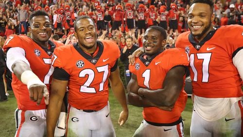 Georgia seniors Lorenzo Carter (from left), Nick Chubb, Sony Michel, and Davin Bellamy celebrate their final home victory 42-13 over Kentucky in a NCAA college football game on Saturday, Nov. 18, 2017, in Athens, Ga. (Curtis Compton/Atlanta Journal-Constitution/TNS)