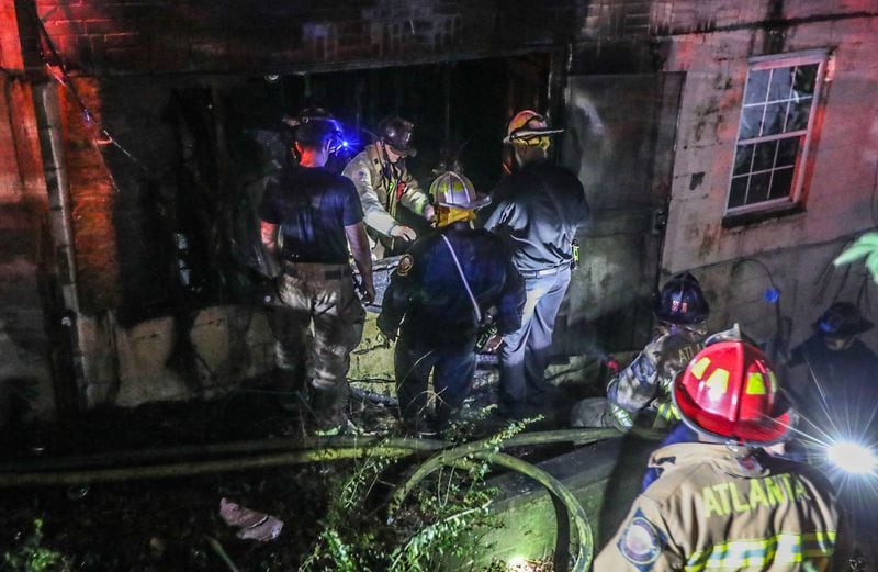 Atlanta fire crews examine a hole in a fire-burned floor at a rooming house on the corner of Burbank and Martin Luther King Jr. drives. A firefighter was injured when he stepped through a hole in the floor Thursday morning.