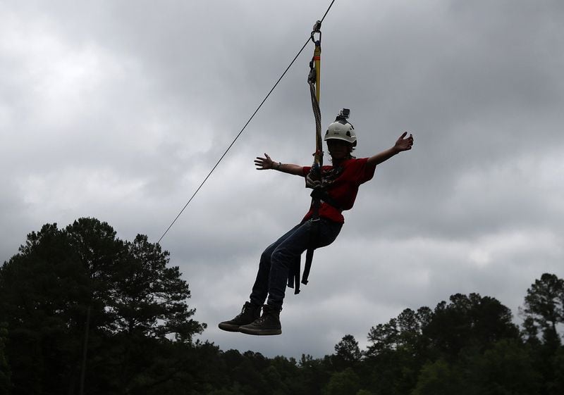 Bronco Reese, overcoming many of his fears over the past year, is the first to ride the zip line from his cabin while attending Camp Braveheart at Camp Twin Lakes on May 31 in Rutledge. CURTIS COMPTON / CCOMPTON@AJC.COM