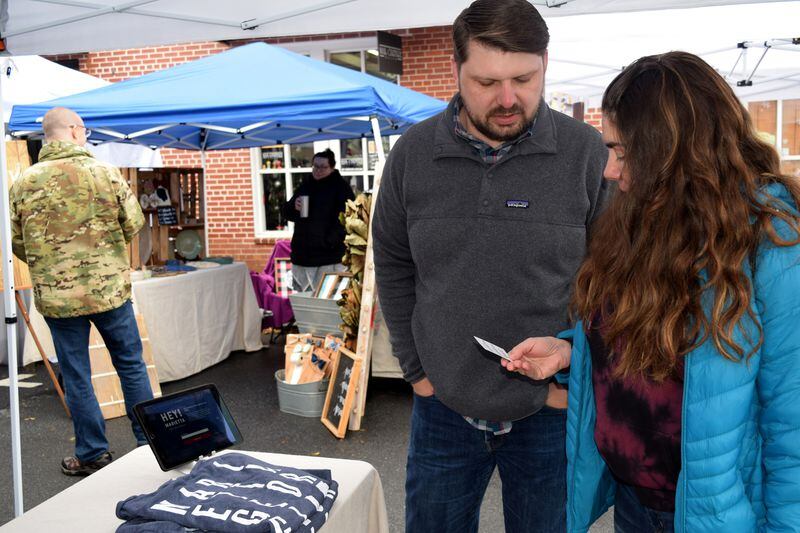 Jon Smith, owner of Hey! Marietta, shares a business card with a potential customer Saturday.