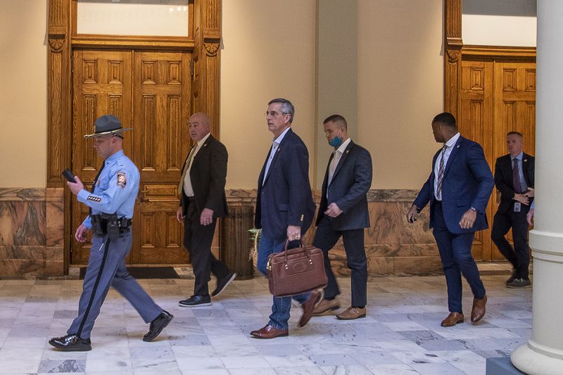 01/06/2021 — Atlanta, Georgia — Lead by a Georgia State Trooper, Georgia Secretary of State Brad Raffensperger (third from left) exits the Georgia State Capitol building after hearing reports of threats in downtown Atlanta, Wednesday, January 6, 2021. American Patriots USA leader Chester Doles had entered the building and was looking to speak with Raffensperger. (Alyssa Pointer / Alyssa.Pointer@ajc.com)