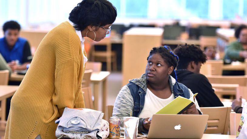Brittany Gantt (left), an adviser with College Advising Corps, helps Ayonna Cameron, 18, senior at Therrell High School, before filling out a federal student financial aid application during an Achieve Atlanta FAFSA Clinic at Therrell High School in Atlanta on Tuesday, Oct. 23, 2018. HYOSUB SHIN / HSHIN@AJC.COM