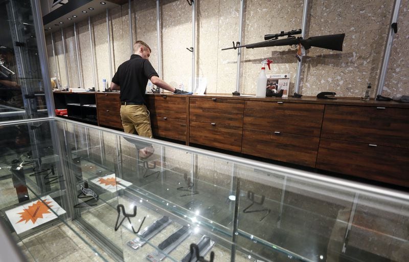 An employee cleans counters at a nearly empty display at Stoddard’s Range and Guns, in Atlanta. Bob Andres / robert.andres@ajc.com
