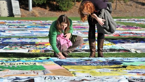 In 2011, Kate Ogorzaly (left) touched one of AIDS Memorial Quilt displays as Ogorzally and Meg Bertram, then both graduate students majoring Global Health, stop for a closer look at the AIDS Memorial Quilt at Emory University’s McDonough Field. CREDIT: Hyosub Shin, hshin@ajc.com