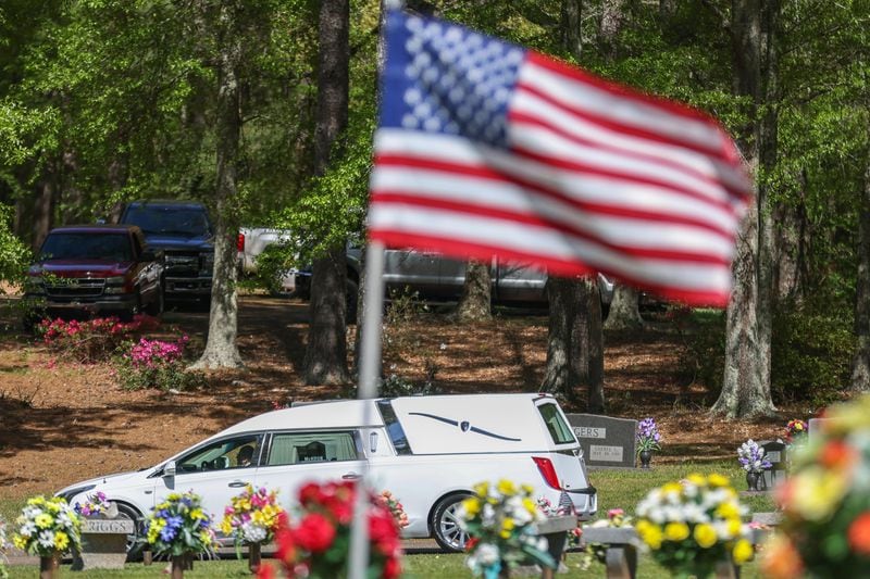 A hearse carrying a Hawk family member arrives at the grave site on Thursday, April 14, 2022, in Newnan, Ga.  The Coweta family was killed during a gun shop robbery.   Branden Camp/For the Atlanta Journal-Constitution