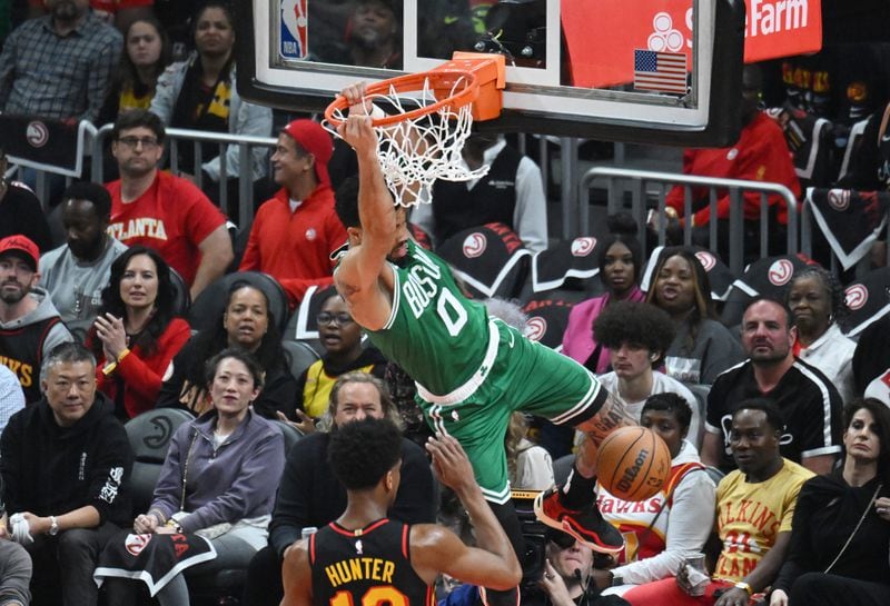 Boston Celtics' forward Jayson Tatum (0) hangs on the basket after dunking the ball. (Hyosub Shin / Hyosub.Shin@ajc.com)